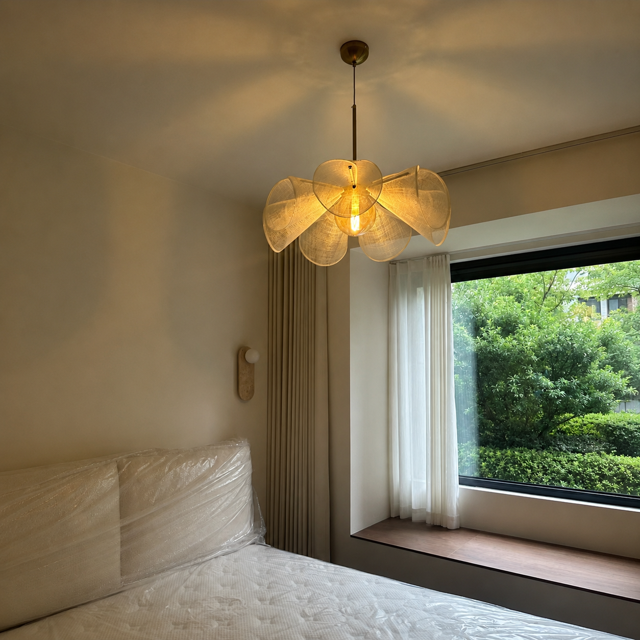 Natural linen chandelier with six petal shades and brass canopy, warm bulb glowing