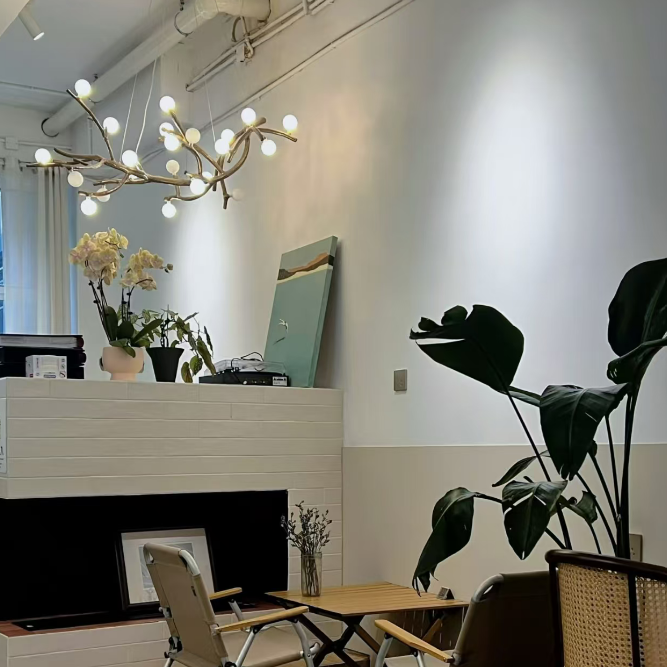 Gold branch chandelier with glowing round bulbs hanging from curved branches.