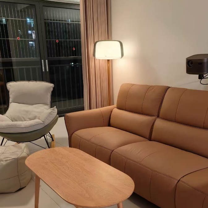 Smoked-glass floor lamp with wood column and round black base by a brown sofa