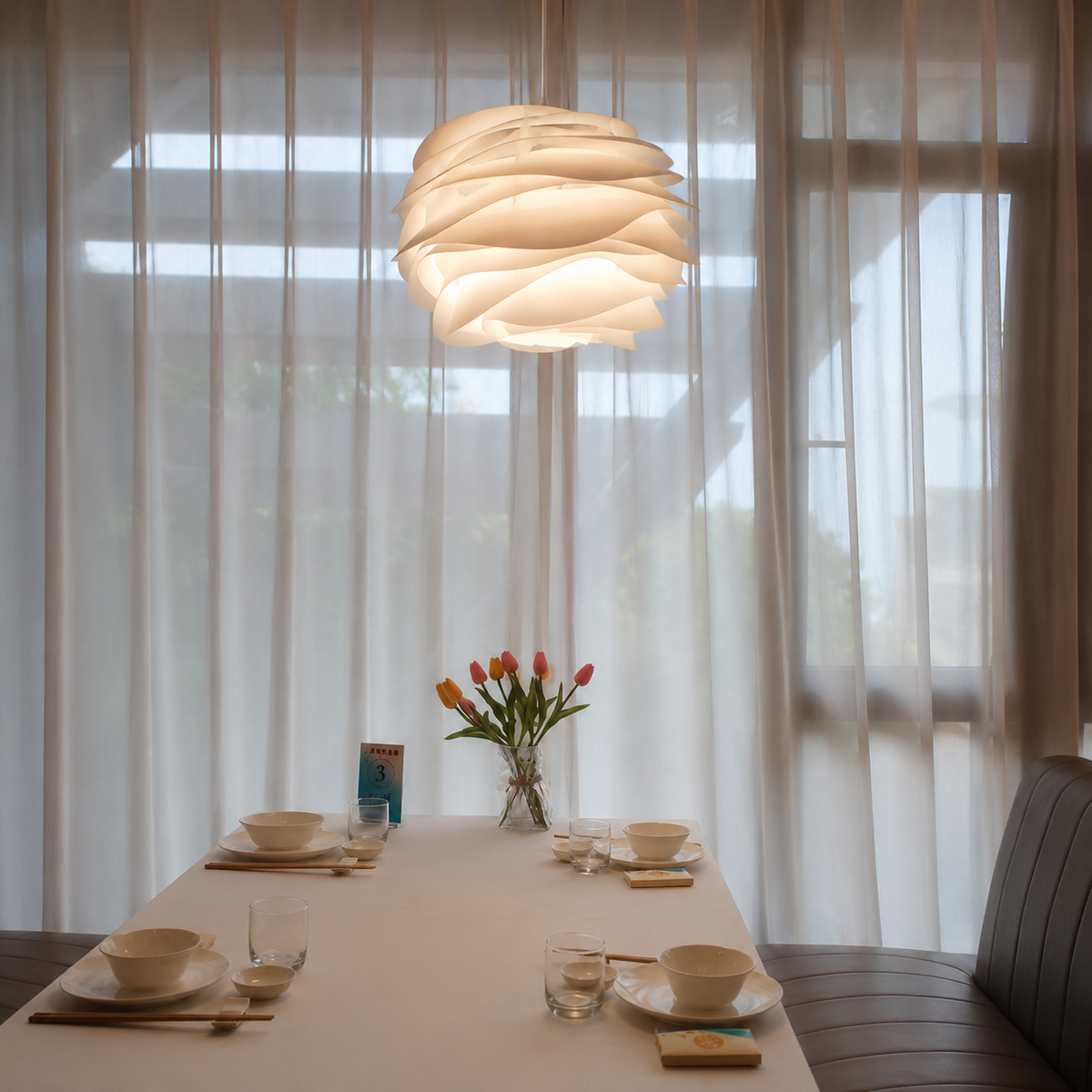 White petal swirl pendant light hanging above dining table with layered petal shade