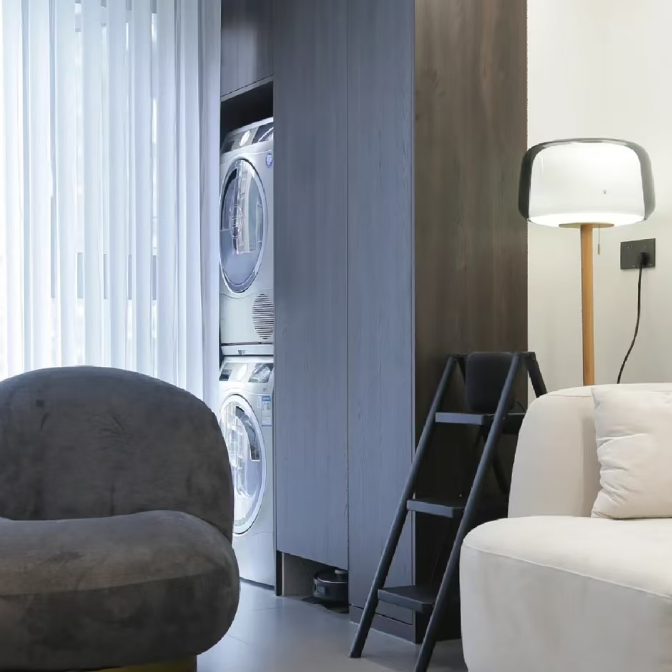 Floor lamp with smoked glass shade and wood stem beside a bed and ladder chair