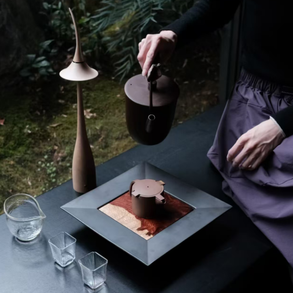 Maple wood cordless table lamp with black curved shade on an outdoor dining table.