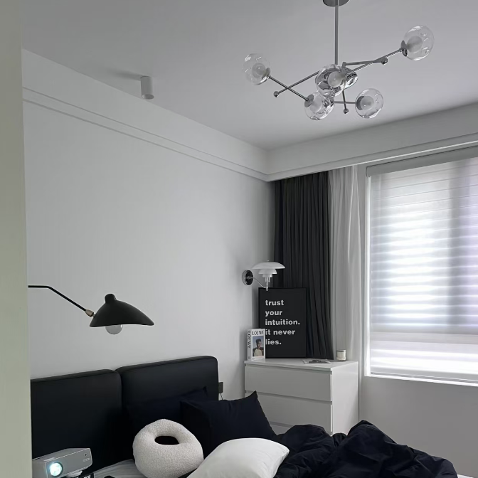 Globe balance chandelier with clear glass bulbs on chrome rods above bed