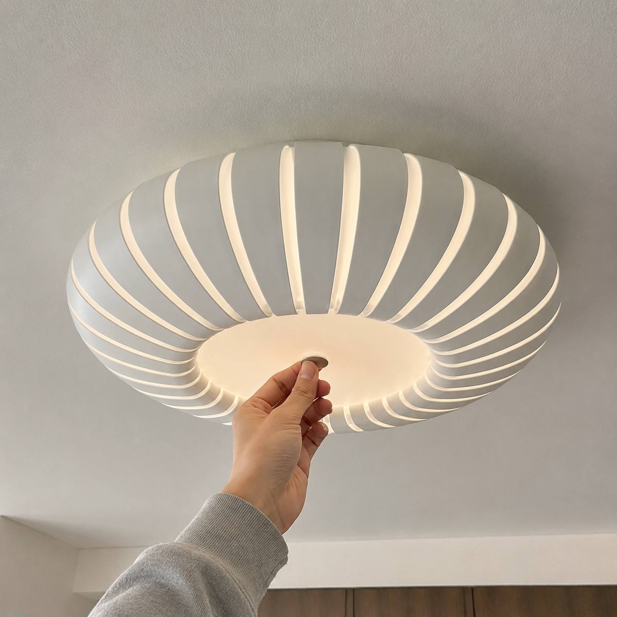 Ribbed flush mount ceiling light ring shown from below with hand adjusting it