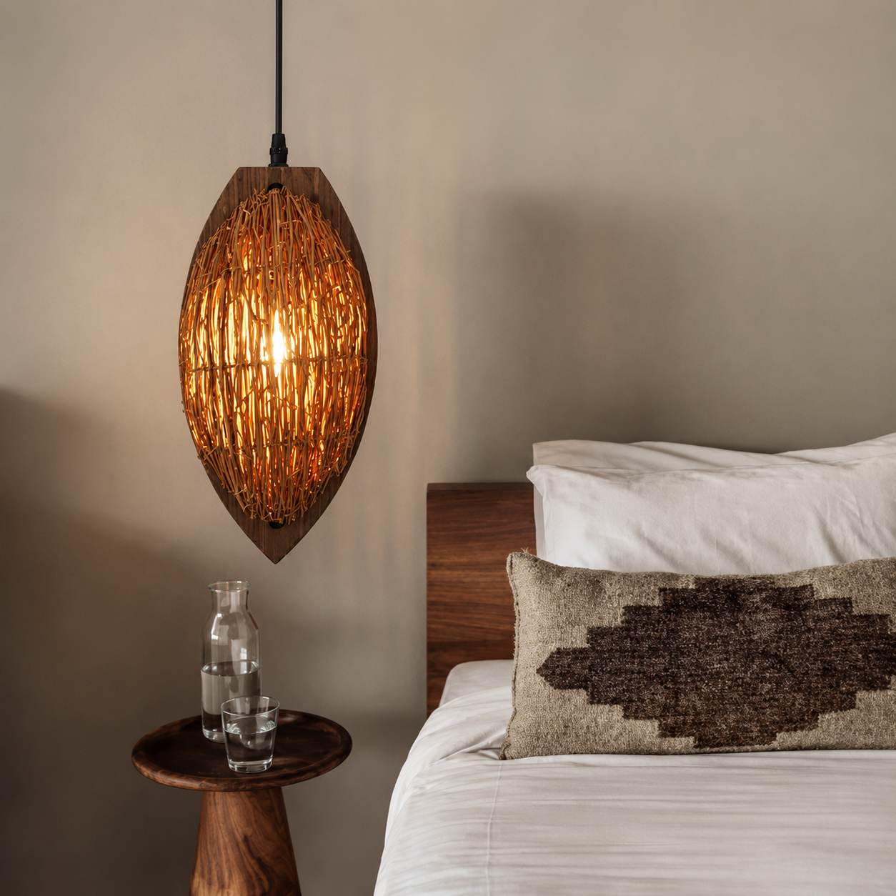 Woven rattan teardrop pendant lamp shade glowing warm amber with black hanging cord.