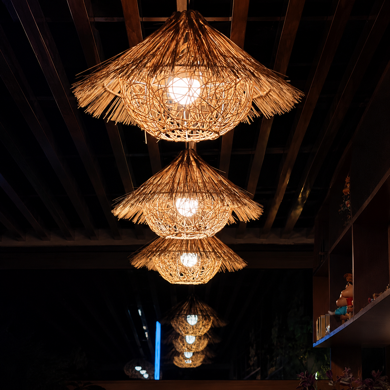 Cluster of woven rattan pendant lights with warm glow under wooden ceiling beams