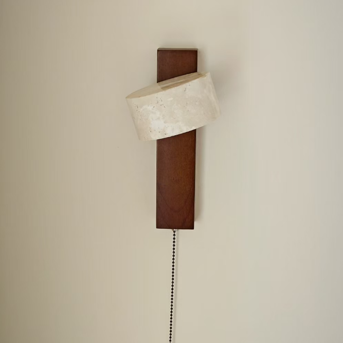 A modern wall-mounted light fixture with a dark brown rectangular backplate, a curved off-white textured shade, and a black pull chain, shown against a plain beige wall.