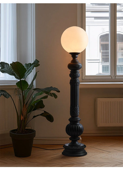 Matte black floor lamp with round globe shade and turned decorative base