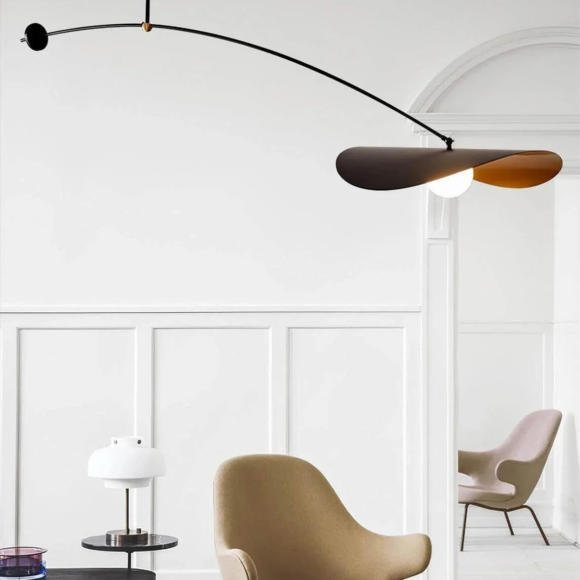 Single-arm pendant light showing black disc shade with gold underside and lit bulb