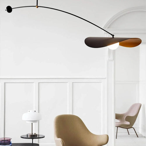 Single-arm pendant light showing black disc shade with gold underside and lit bulb