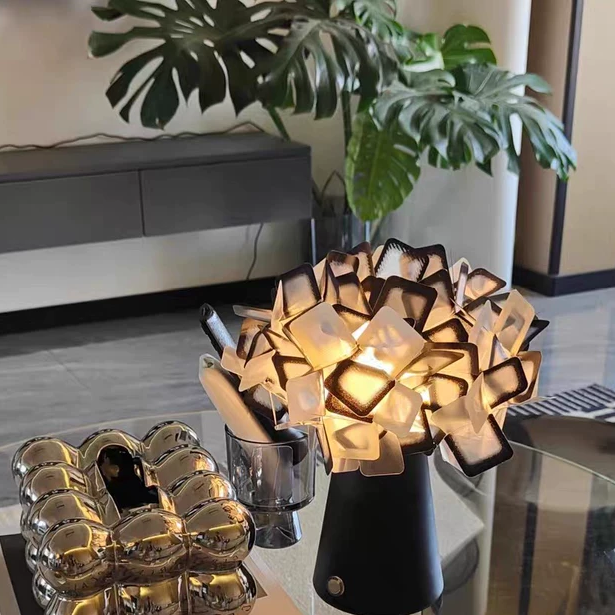 Geometric blossom table lamp with black base and warm white cube petal light.