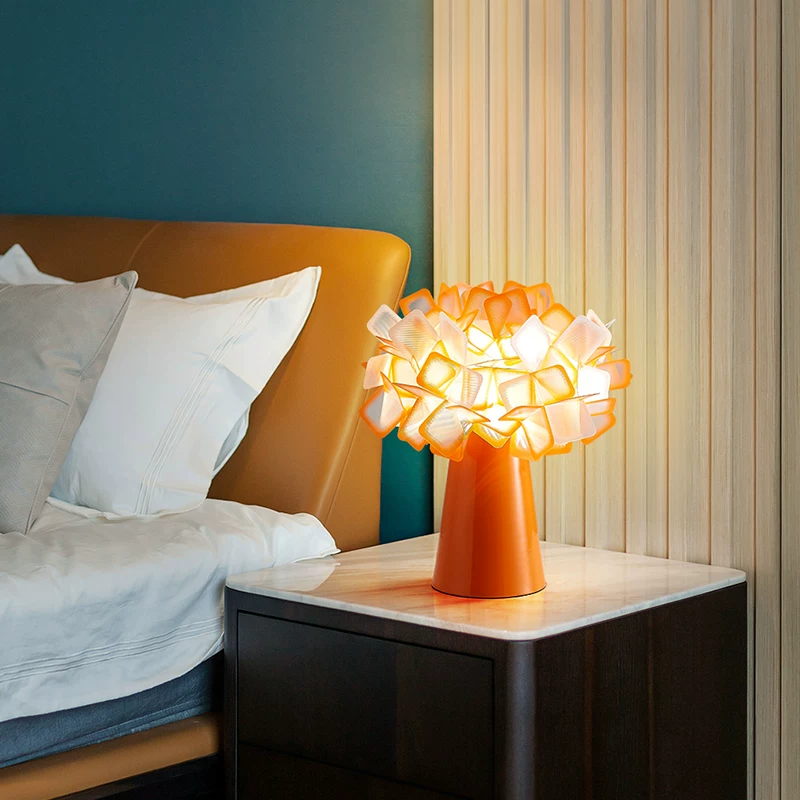 Geometric blossom table lamp with orange base and warm white cube petal shade.