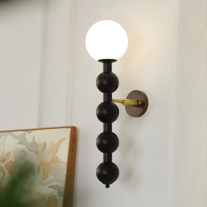 Matte black beaded globe wall lamp with white globe shade on round backplate
