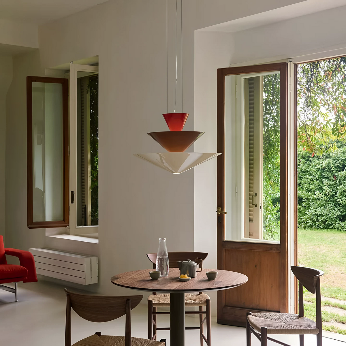 Red tiered cone pendant light with three stacked shades above a small table
