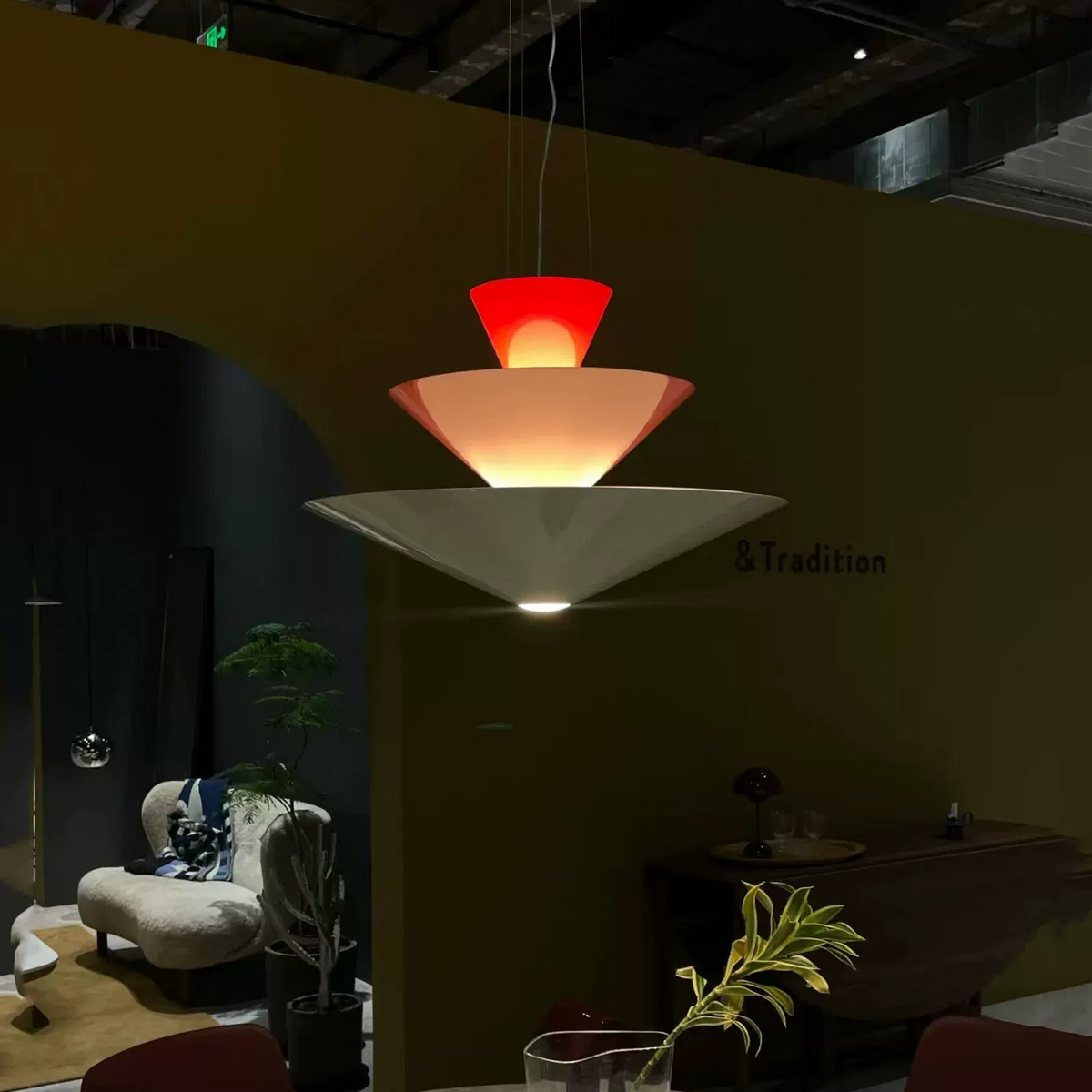 Tiered geometric cone pendant light with red top cone and warm glow