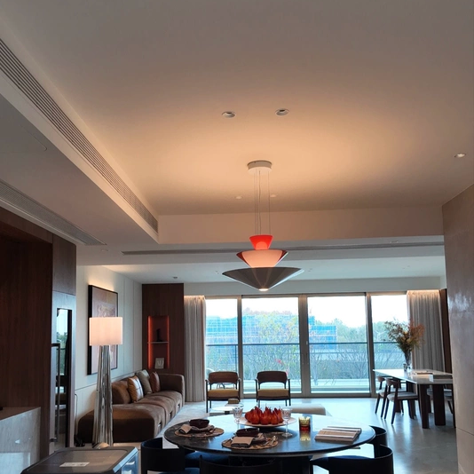 Red tiered cone pendant light with three stacked shades hanging in a large room