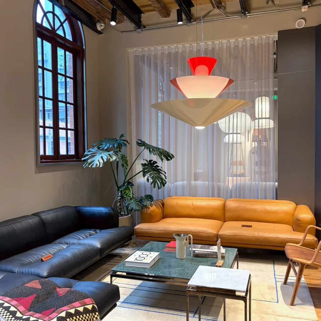 Red and off-white tiered cone pendant light with three stacked shades in a living room