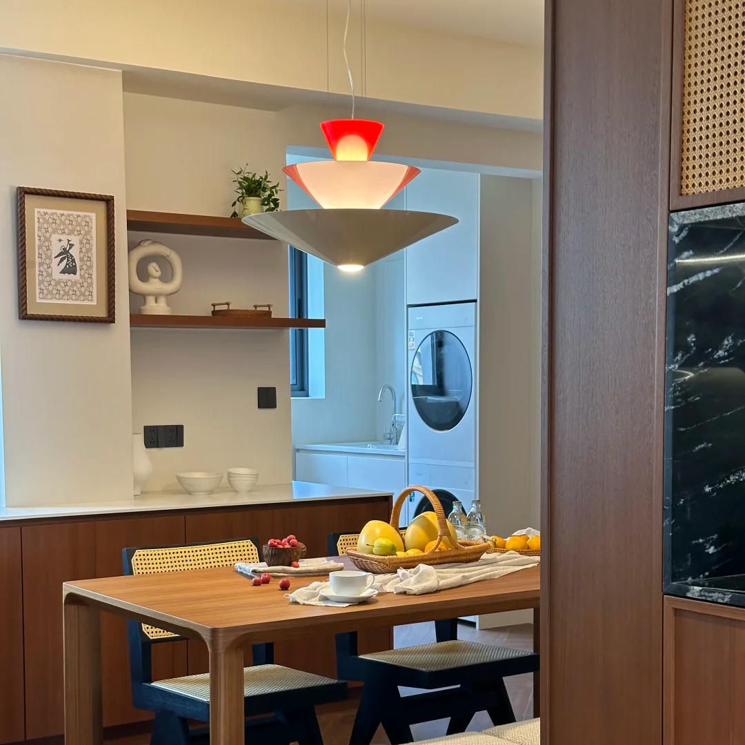 Red tiered cone pendant light with three stacked shades over a dining table