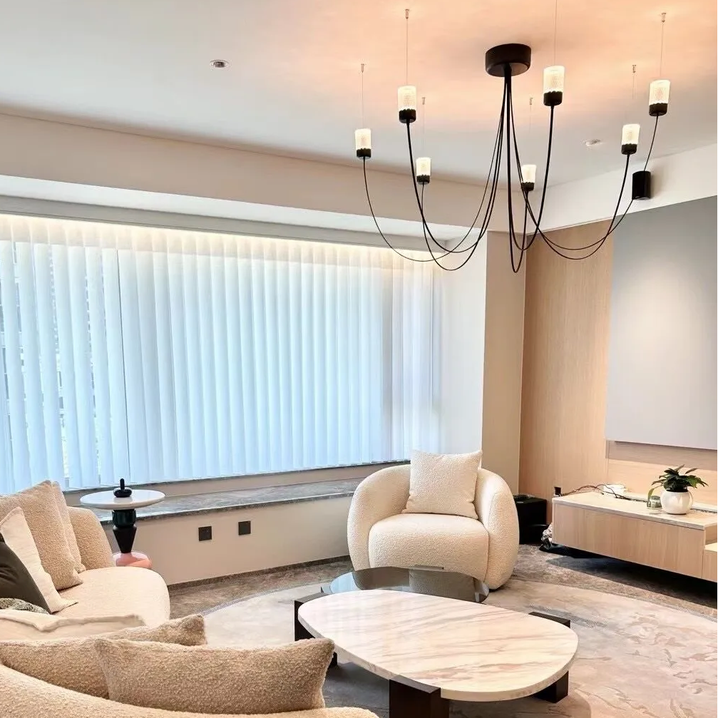 Modern catenary chandelier with black canopy, sweeping curved arms, and cylinder fabric shades