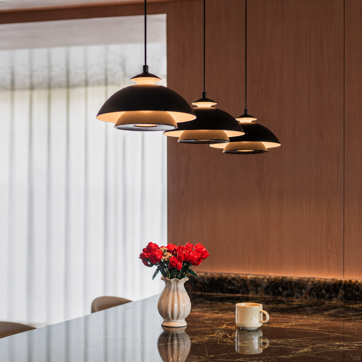 Black dome pendant light cluster with layered shades glowing above a table.