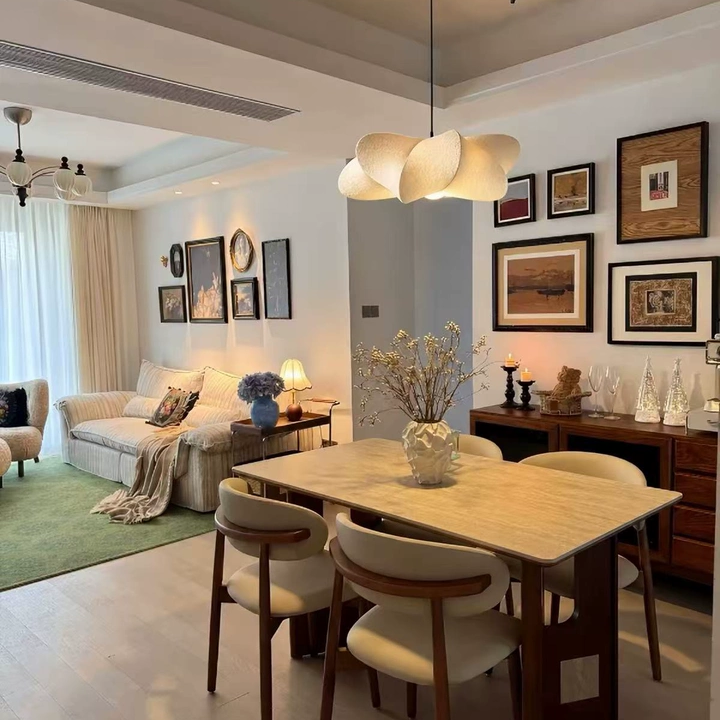 Sculptural silk petal pendant light with cream beige shades suspended above table in living room