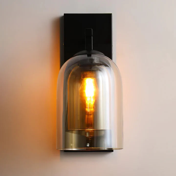 Smoke gray tinted bell jar wall sconce with black backplate and glowing bulb