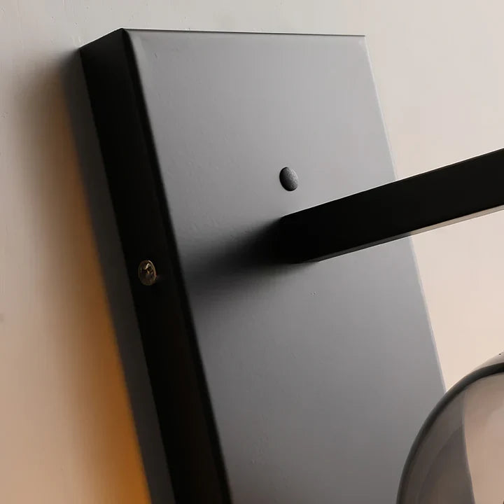 Black wall-mounted sconce arm with mounting plate and small screw detail