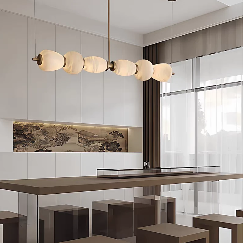 Gold linear chandelier with frosted round alabaster shades over kitchen counter