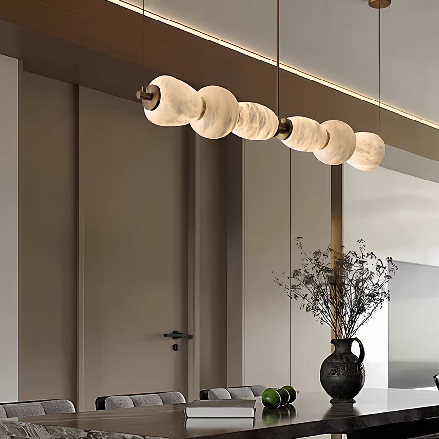 Gold linear chandelier with frosted disc shades suspended above living room seating