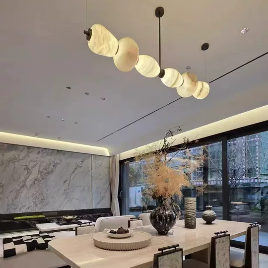 Linear chandelier with gold rod and frosted circular shades in open-plan living space