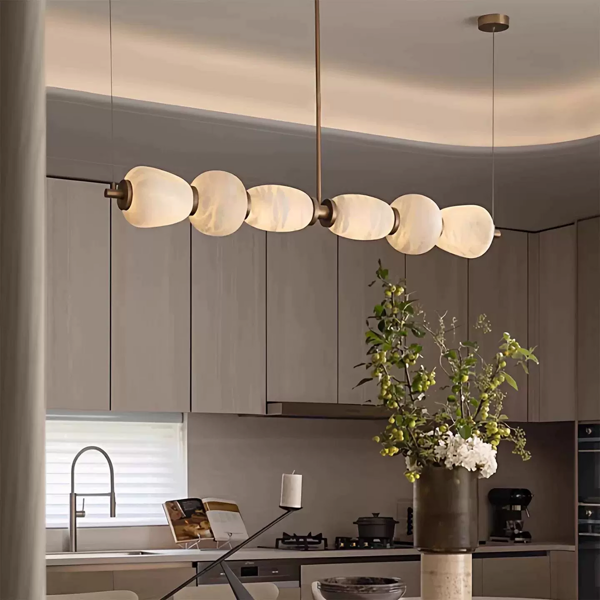 Gold linear chandelier with frosted alabaster disc shades above kitchen island