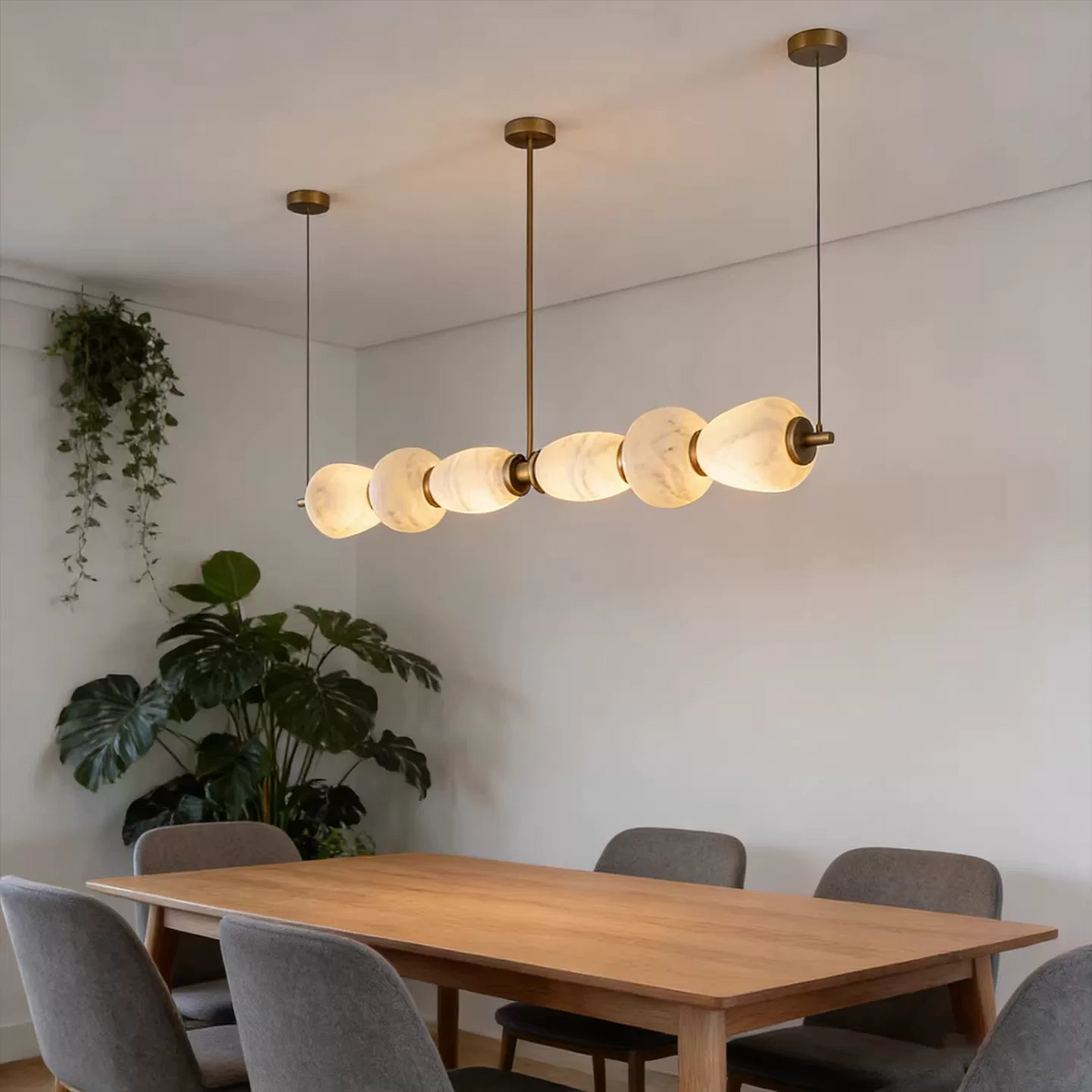Linear gold chandelier with frosted disc shades hanging over dining table