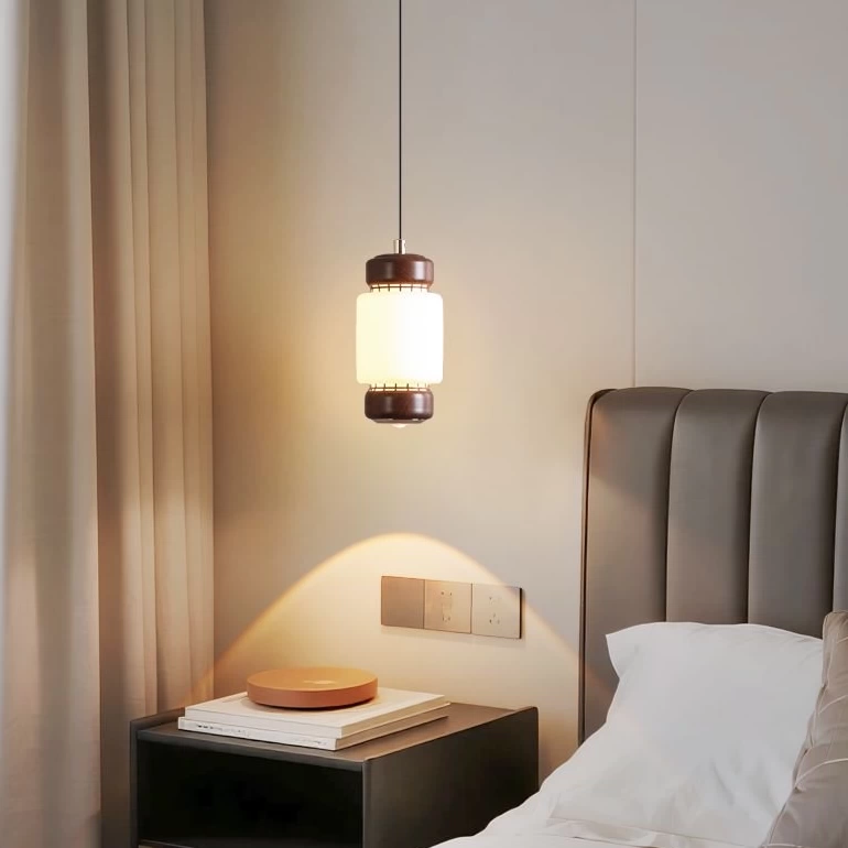 Frosted glass mini pendant light with walnut ring details, hanging from a ceiling cord