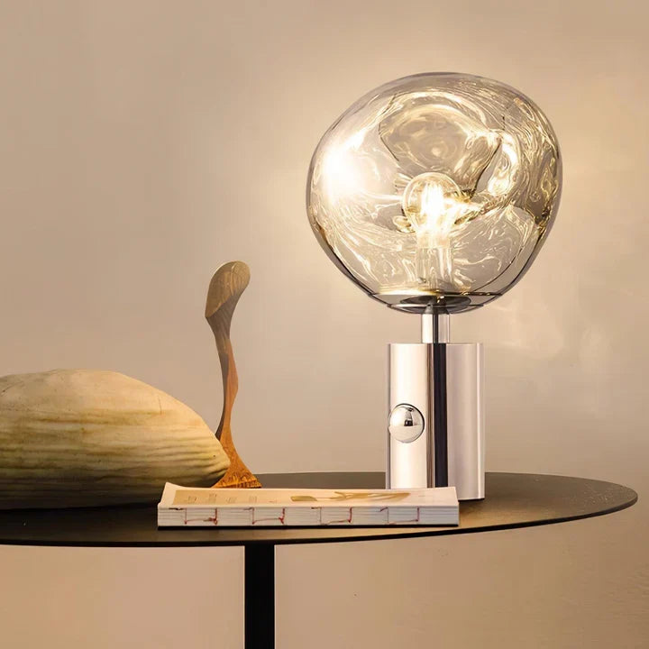 Silver table lamp with clear glass globe shade and glowing bulb