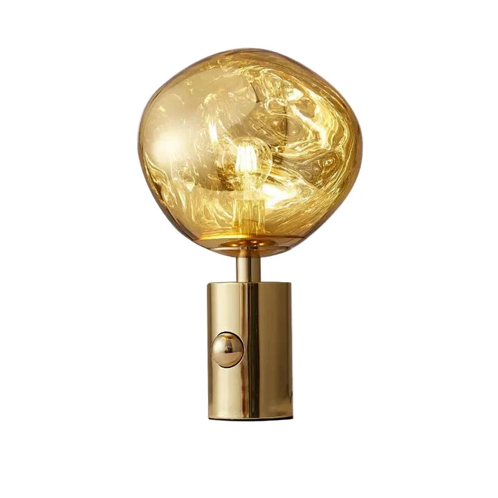 Gold table lamp with golden glass globe shade and glowing bulb