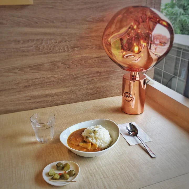 Copper table lamp with amber glass globe shade and glowing bulb