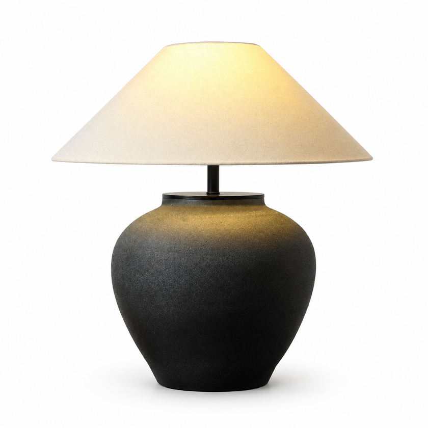 Ceramic table lamp with dark vase base and beige fabric drum shade on a stand