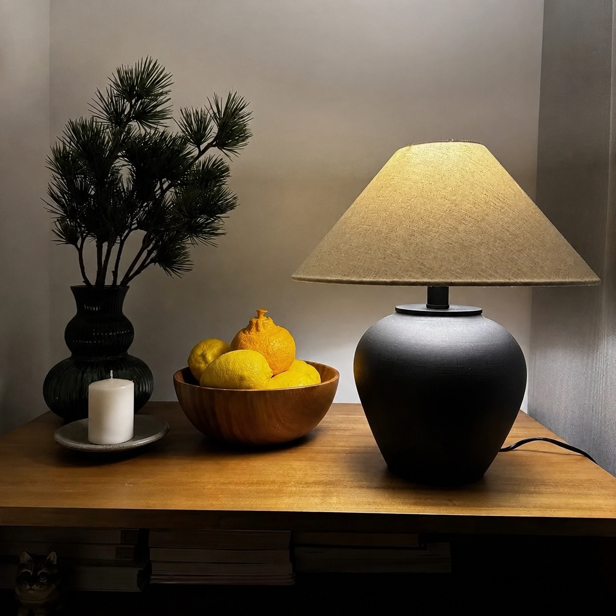 Ceramic table lamp with black ceramic base and beige fabric drum shade on a tabletop