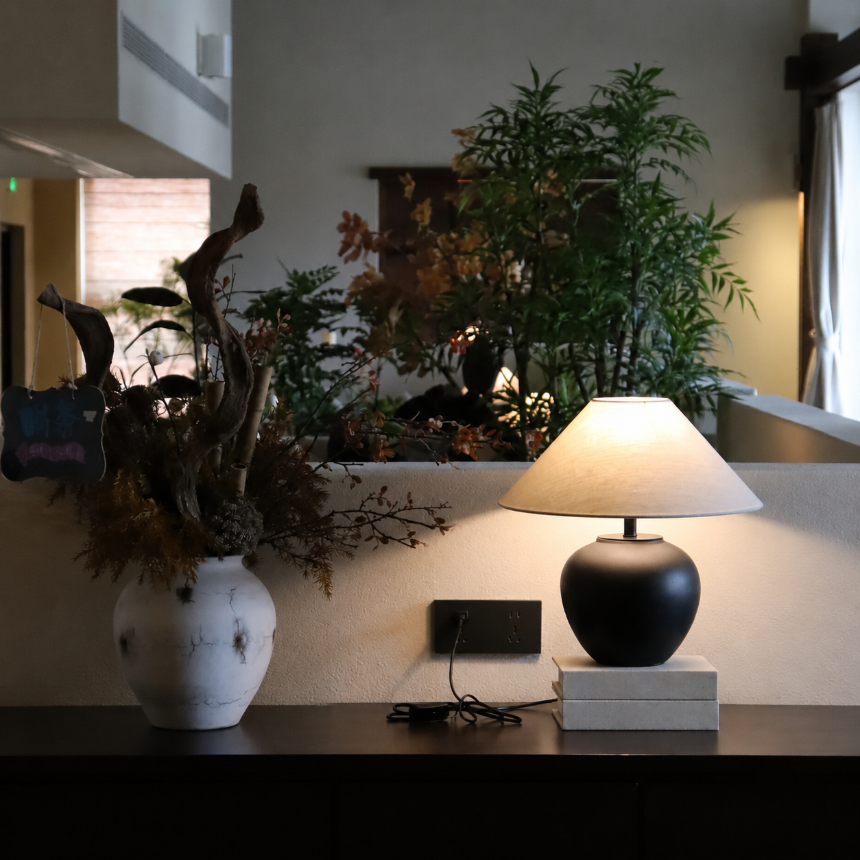 Ceramic table lamp with dark rounded ceramic base and beige fabric drum shade