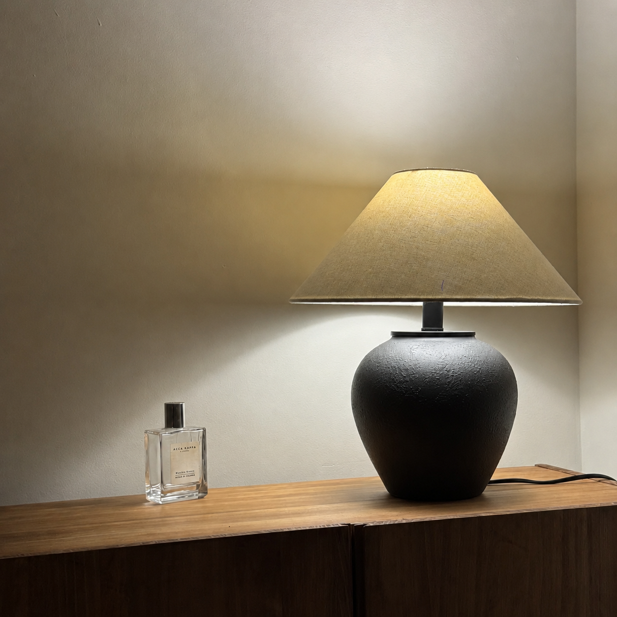 Ceramic table lamp with textured black ceramic base and beige drum fabric shade