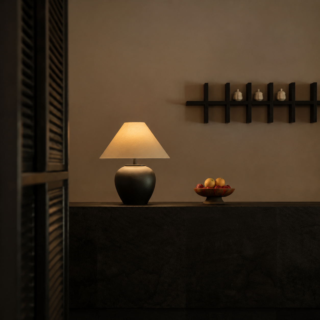 Ceramic table lamp with dark ceramic base and beige fabric drum shade on a console