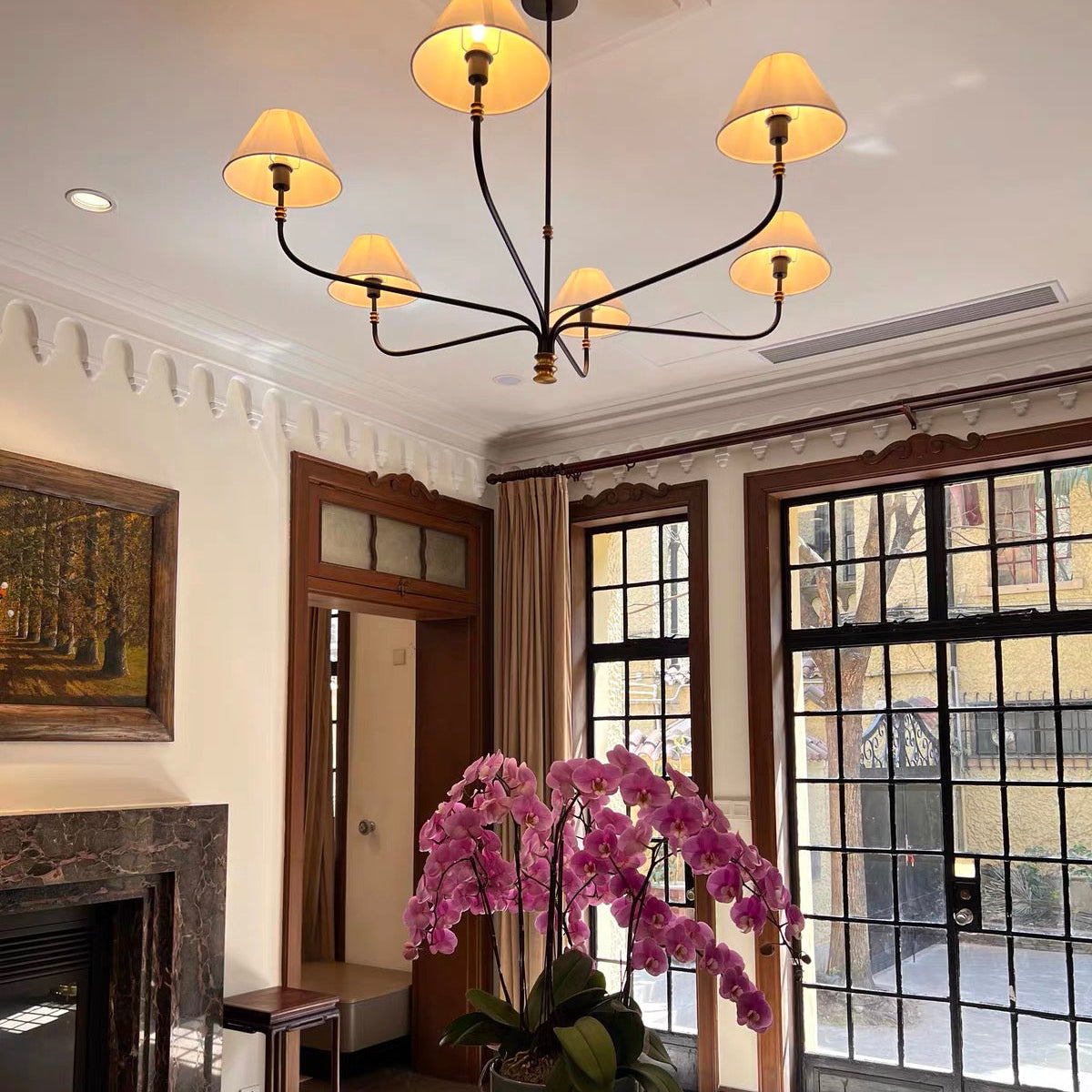 Ceiling chandelier with black arms, gold accents, and cream fabric shades in an entry area.