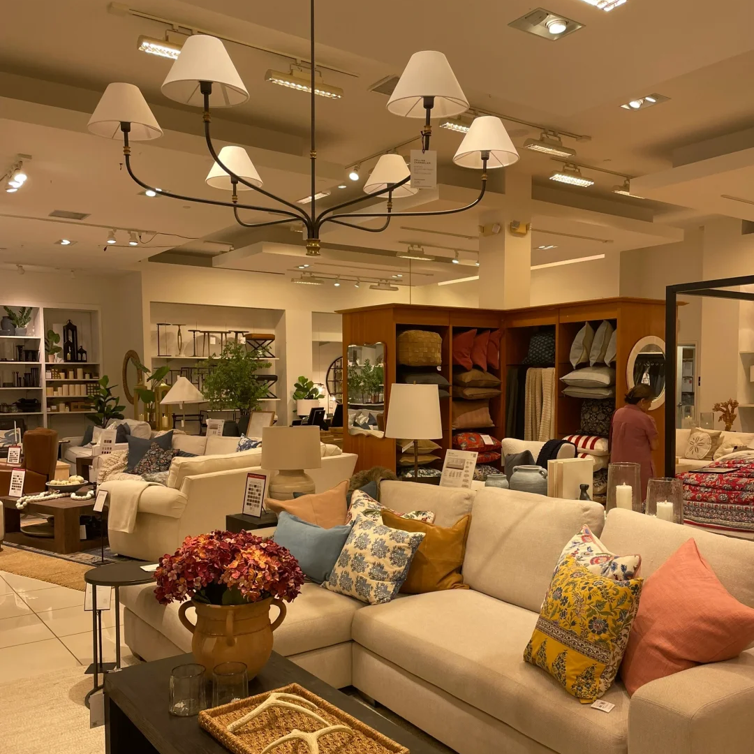 Modern chandelier with black arms and cream fabric shades in a retail-style showroom.