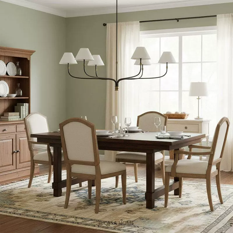 Fabric shade chandelier with black arms, cream shades, and gold accents over a dining table.