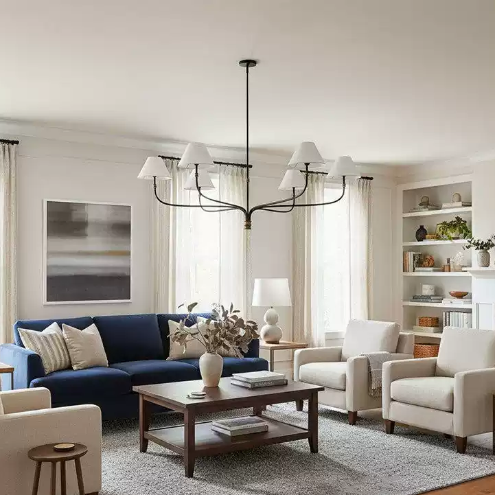 Cream fabric shade chandelier with black curved arms and gold center detail in a living room.