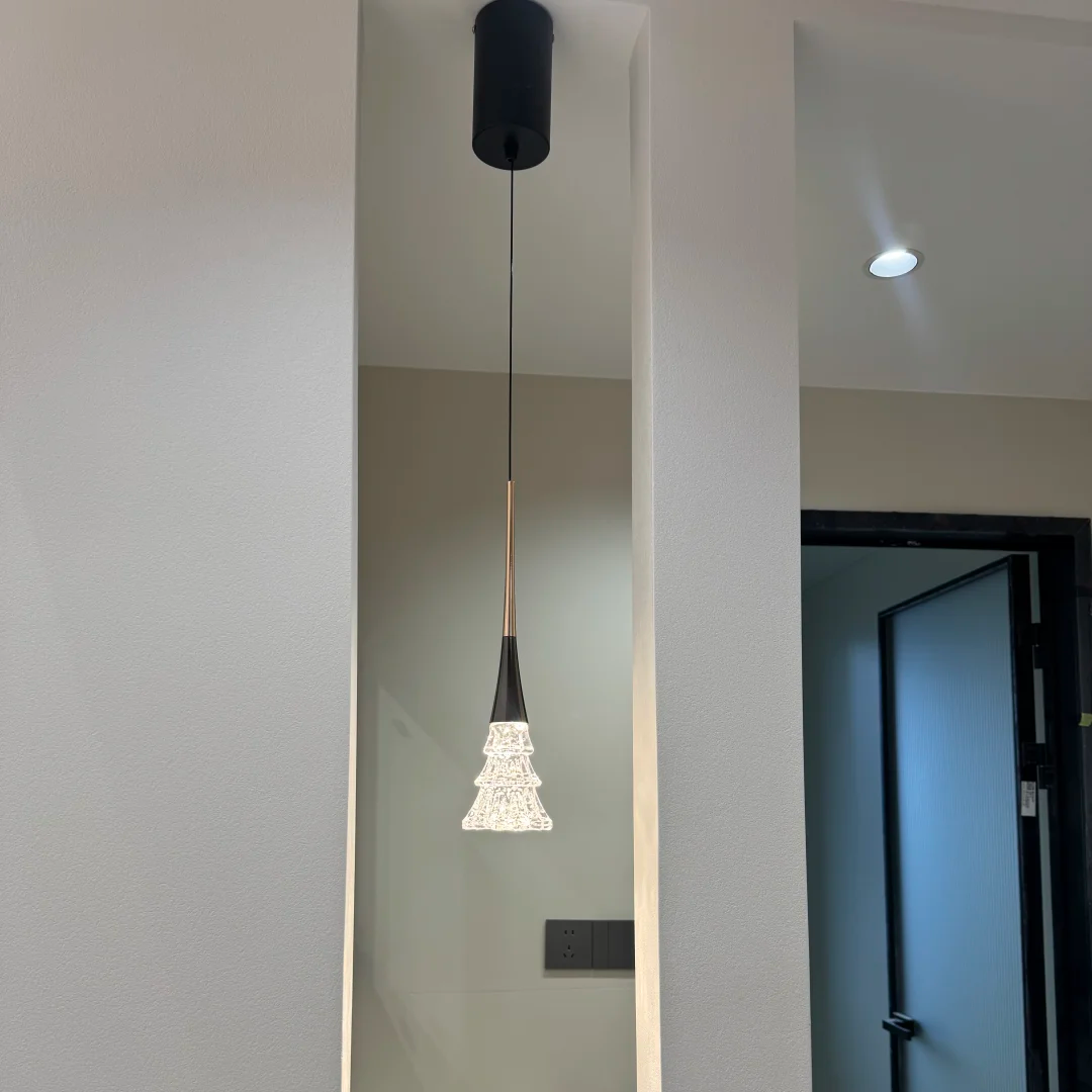 Matte black pendant light with crystal tree diffuser, glowing warm from ceiling