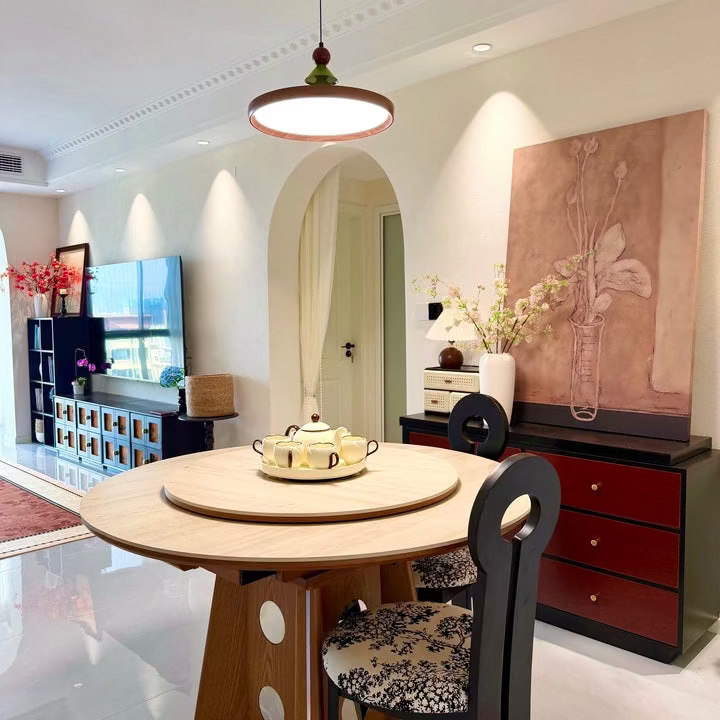 Pendant light with wood disc shade, pine-tree topper and red bead over round table