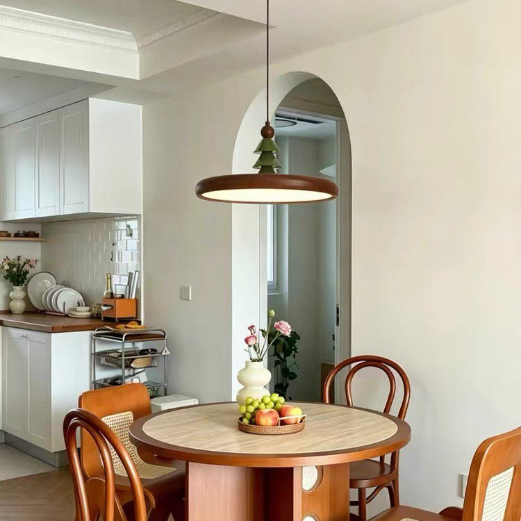 Wood disc pendant light with pine-topped finial, warm amber glow