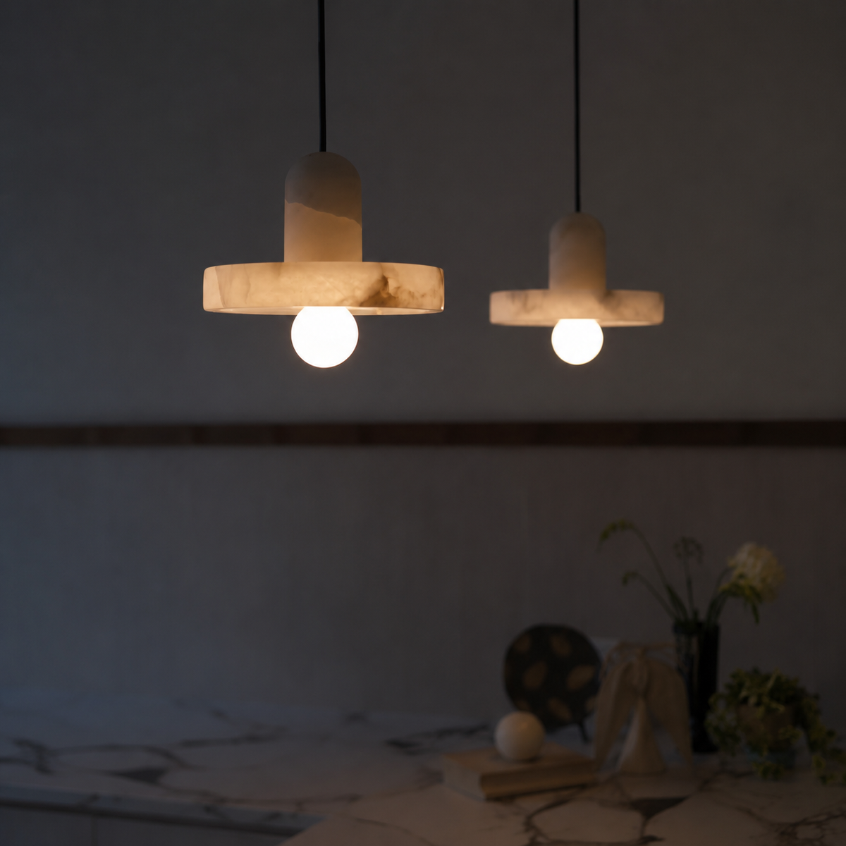 Alabaster fishline pendant light pair with warm glowing globe bulbs under stone crossbars