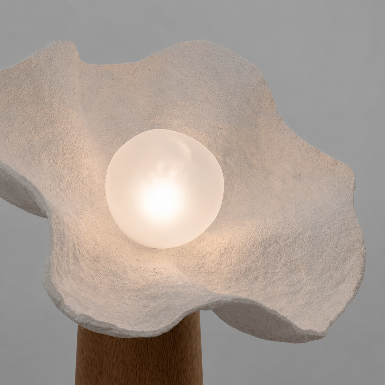 Mushroom floor lamp close-up: textured shade with glowing bulb on wood stem